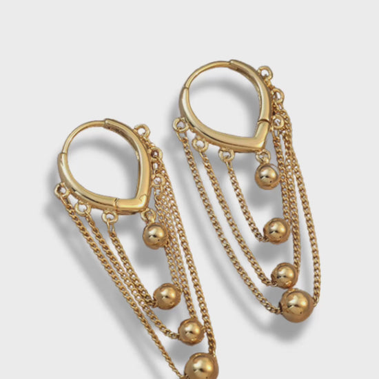 Ball and Chain Hoop Earrings.&nbsp; These stunning Gold Hoop Earrings are embellished with multiple layers of gold chains and adorned with graduating sizes of gold beads. An effortlessly chic accessory, these gold dangle earrings will add a statement-making touch to your outfit