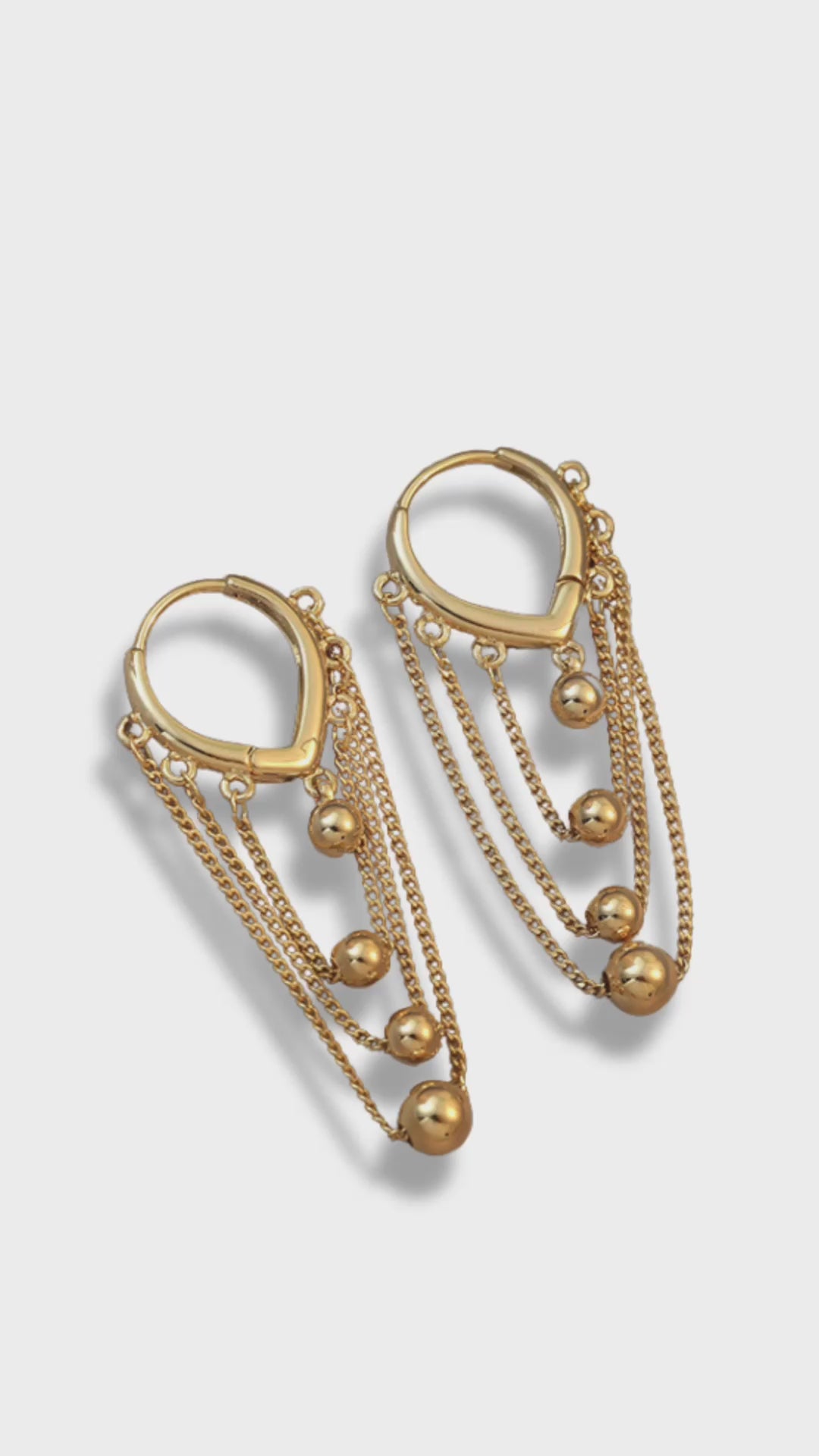 Ball and Chain Hoop Earrings.&nbsp; These stunning Gold Hoop Earrings are embellished with multiple layers of gold chains and adorned with graduating sizes of gold beads. An effortlessly chic accessory, these gold dangle earrings will add a statement-making touch to your outfit